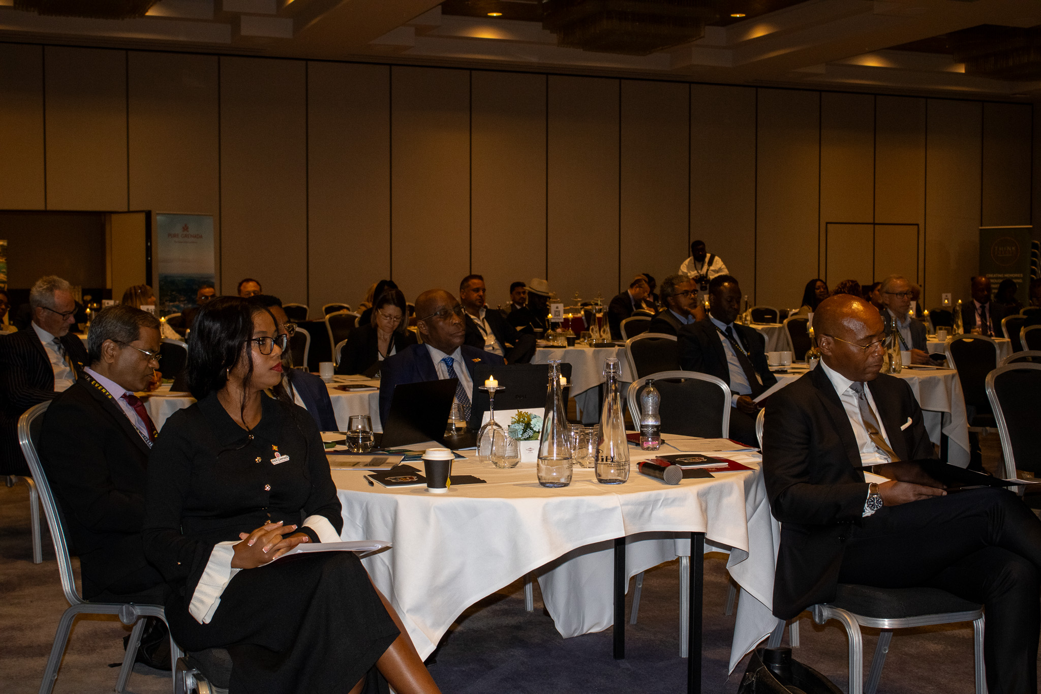 Audience seated at tables during a Grenada event